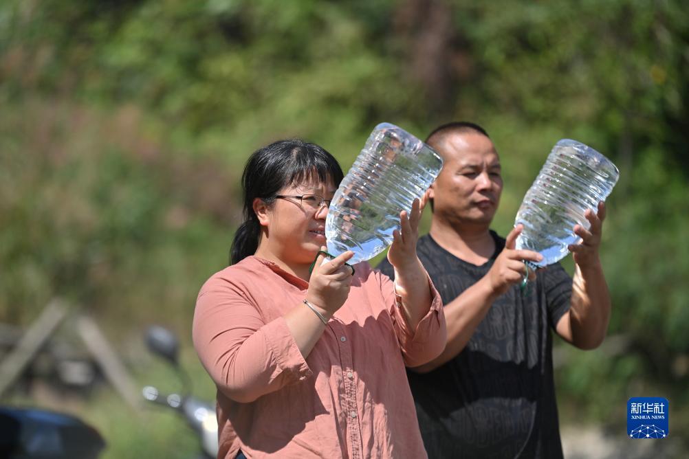 楊寧（左）在查看村民剛剛采集的水樣，為山泉水引水工程做準(zhǔn)備（10月8日攝）。新華社記者 黃孝邦 攝